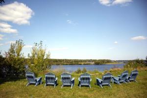 a row of chairs sitting in the grass near a lake at Motel Moreau in Saint-Félicien