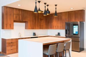 a kitchen with wooden cabinets and a kitchen island with bar stools at Courtyard by Marriott Waterloo Cedar Falls in Waterloo