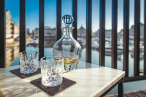 a bottle of whiskey and two glasses on a table at Waters Edge - stylish marina retreat in Pevensey