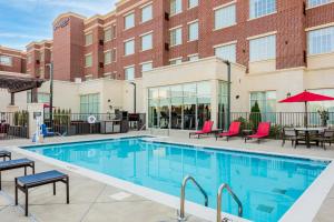 a swimming pool with tables and chairs in front of a building at Residence Inn Franklin Berry Farms in Franklin