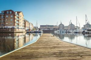 a wooden dock with boats in a marina at Waters Edge - stylish marina retreat in Pevensey