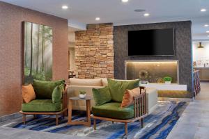 a lobby with two chairs and a tv on a wall at Fairfield Inn & Suites by Marriott Albany Airport in Albany