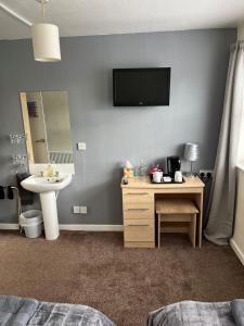 a bedroom with a sink and a desk with a tv on the wall at The Lenbrook in Blackpool