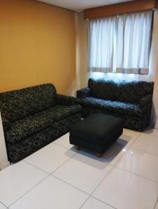 a living room with a couch and a ottoman at Brasília Santana Gold Flat in Sao Paulo