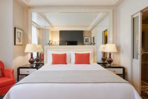 パリにあるプリンスドガル ア ラグジュアリーコレクションホテル パリのベッドルーム(オレンジ色の枕が付いた大きな白いベッド付)