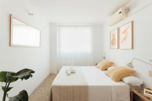 een witte slaapkamer met een bed en een plant bij Casa Jam Barcelona in Barcelona