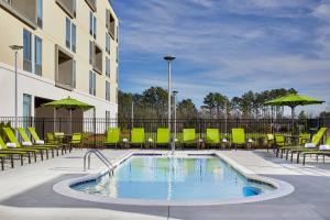 einen Pool mit Stühlen und ein Gebäude in der Unterkunft SpringHill Suites Charlotte at Carowinds in Charlotte