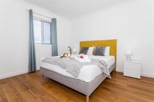 a white bedroom with a large bed with flowers on it at Oásis Fonte Grande in Santo António