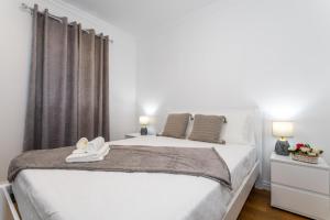 a bedroom with a white bed with two white shoes on it at Oásis Fonte Grande in Santo António