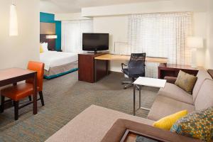 a hotel room with a bed and a living room at Residence Inn by Marriott Detroit Livonia in Livonia