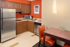 a kitchen with a table and a stainless steel refrigerator at Residence Inn by Marriott Detroit Livonia in Livonia