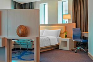 a bedroom with a bed and a desk and a chair at Le Royal Meridien Abu Dhabi in Abu Dhabi