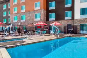 a swimming pool with tables and chairs in front of a building at TownePlace Suites by Marriott Bakersfield West in Bakersfield