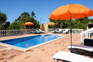 - une piscine avec un parasol orange, des chaises et des tables dans l'établissement Casa Rina, à Lagoa