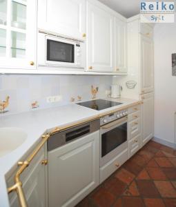 a white kitchen with a sink and a microwave at Margaretheneck, sehr strandnah und zentral in Westerland (Sylt)