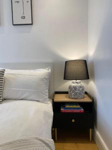 a bed with a side table with a lamp on it at New stylish Fulham apartment - 2 bed in London