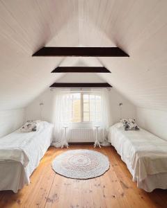 a attic room with two beds and a window at Knappagården in Glemminge