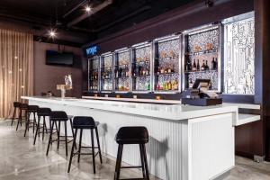 een bar met krukken en een rij alcoholflessen bij Aloft Atlanta at The Battery Atlanta in Atlanta