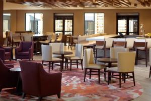 a restaurant with tables and chairs and a bar at Atlanta Marriott Peachtree Corners in Norcross