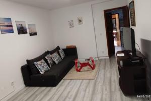 a living room with a black couch and a television at Beach, surf and golf apartment near Lisbon in Aroeira