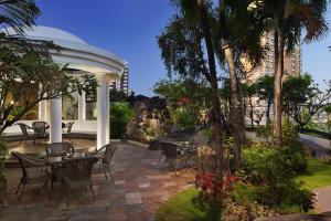 a patio with tables and chairs and palm trees at Sheraton Manila Bay in Manila