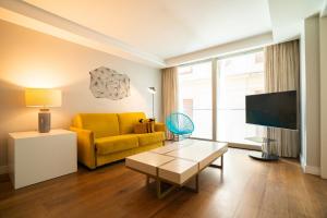 uma sala de estar com um sofá amarelo e uma televisão em SmartRental Collection Centric II em Madrid