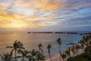 un tramonto sull'oceano con palme su una spiaggia di JW Marriott Maldives Resort & Spa a Funadhoo