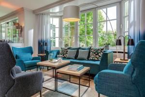 a living room with blue furniture and windows at Courtyard by Marriott Hamburg Airport in Hamburg