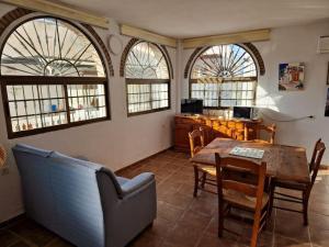 Casa El Banco في Iznate: غرفة معيشة مع طاولة وكراسي ونوافذ