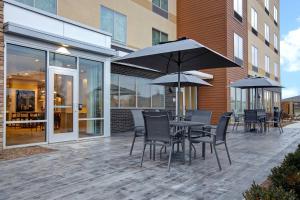 patio ze stołem, krzesłami i parasolami w obiekcie Fairfield Inn & Suites by Marriott Chicago Bolingbrook w mieście Bolingbrook