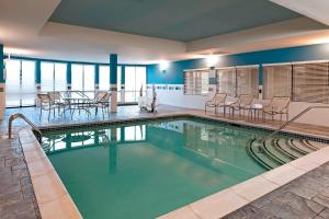 a large swimming pool with chairs and a table at Courtyard Hartford Farmington in Farmington