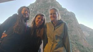 três mulheres em pé em frente a uma montanha em Picos House em Machu Picchu
