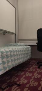 un letto in una stanza con tappeto e sedia di LA CASITA DE LA PUERTA DE CARMONA a Siviglia