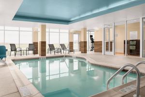 a swimming pool in a building with chairs and tables at Fairfield Inn & Suites by Marriott Memphis Marion, AR in Marion