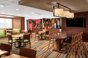 a dining room with tables and chairs and a flat screen tv at Fairfield Inn & Suites by Marriott Memphis Marion, AR in Marion