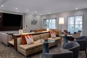 a living room with a couch and chairs and a flat screen tv at Courtyard by Marriott Miami Aventura Mall in Aventura