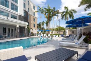 a swimming pool with chairs and umbrellas at a hotel at Residence Inn Palm Beach Gardens in Palm Beach Gardens