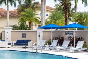 a pool with chairs and umbrellas next to a hotel at Residence Inn Palm Beach Gardens in Palm Beach Gardens