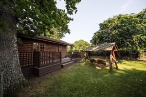uma cabana de madeira com um parque infantil ao lado de uma árvore em Birch Lodge em Swanage