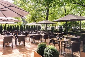 ein Restaurant mit Tischen, Stühlen und Sonnenschirmen in der Unterkunft Munich Marriott Hotel in München