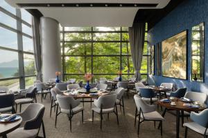 香港的住宿－香港數碼港艾美酒店，餐厅设有桌椅和大窗户。