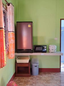 a counter with a microwave and a tv on a wall at Teacher House in Phra Ae beach