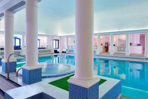 a large swimming pool with columns and a large swimming pool at Hanbury Manor Marriott Hotel & Country Club in Ware