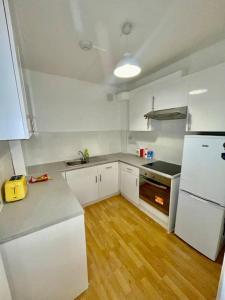a kitchen with white appliances and a wooden floor at 2 bedroom near Euston, King's Cross in London