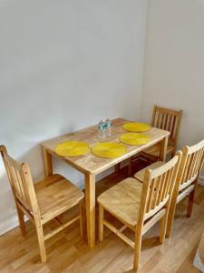a wooden table with four chairs and yellow plates on it at 2 bedroom near Euston, King's Cross in London