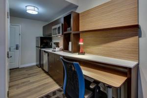 a kitchen with a counter and a desk with a blue chair at TownePlace Suites by Marriott Mobile Saraland in Saraland