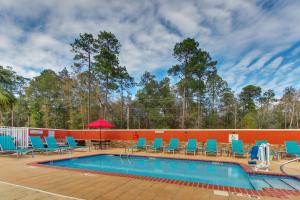 una piscina con tumbonas azules y una pared roja en TownePlace Suites by Marriott Mobile Saraland, en Saraland