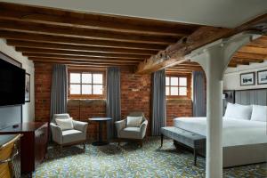 a bedroom with a bed and two chairs and a television at Manchester Marriott Victoria & Albert Hotel in Manchester