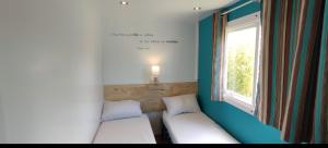 - 2 lits dans une petite chambre avec fenêtre dans l'établissement Bungalow au pied du Luberon, à Saint-Martin-de-la-Brasque