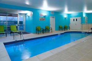 uma piscina com cadeiras e mesas verdes em SpringHill Suites by Marriott East Lansing University Area, Lansing Area em East Lansing